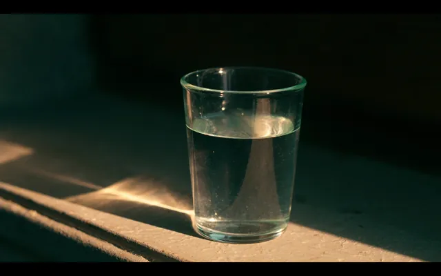 Bicchiere d'acqua su un davanzale di pietra nella luce del mattino
