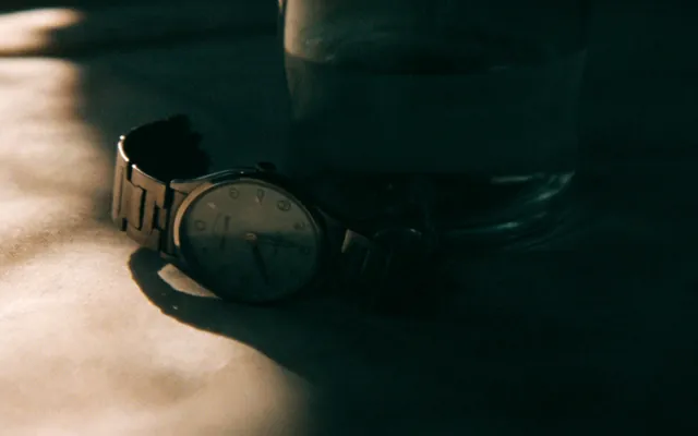 Orologio da polso su un panno accanto a un bicchiere d'acqua