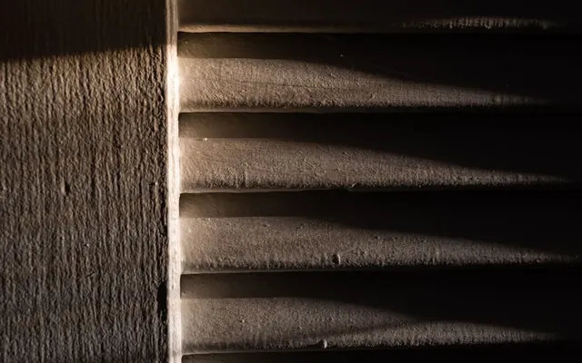 Luce che filtra dalle veneziane in una stanza buia