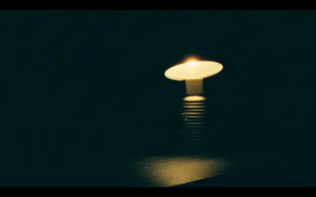 Piccola lampada da tavolo con luce ambrata accesa in una stanza buia
