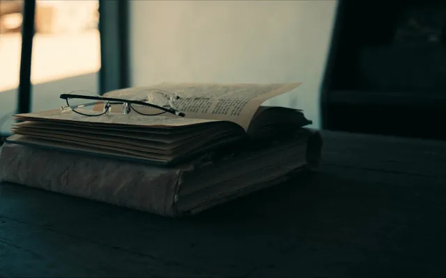 Libro aperto e occhiali da lettura su un tavolo di legno